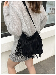 Detail of black suede shoulder bag with long fringes and adjustable strap buckles