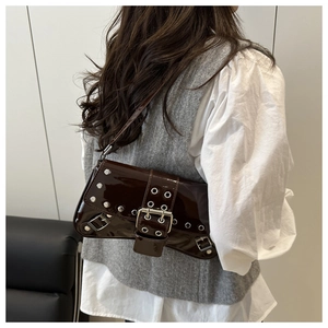 Detail view of coffee patent leather baguette bag with silver studs and metal buckle