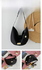 Detail of black crescent crossbody bag with adjustable strap and detachable round coin purse