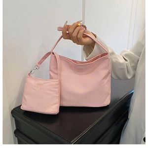 Close-up of pink nylon shoulder bag with embossed letters and matching coin purse