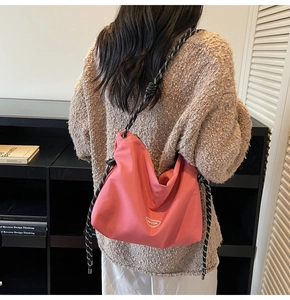 Detail of coral pink nylon crossbody bag with black and white rope shoulder strap
