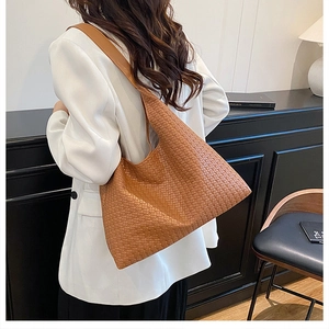 Rear view of model wearing a brown woven PU leather hobo bag with wide shoulder strap