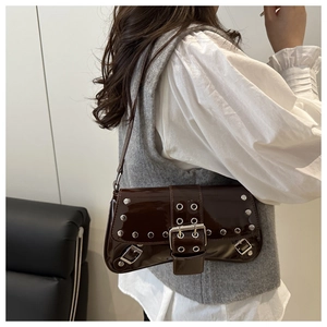 Detail view of mocha brown patent leather shoulder bag with silver studs and metal eyelets
