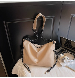 Dettaglio della borsa a tracolla in nylon beige con logo e tracolla intrecciata bicolore