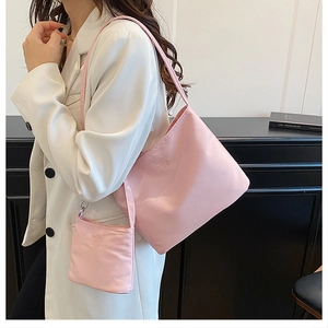 Pink nylon tote bag set with detachable mini pouch shown on shoulder in a lifestyle view