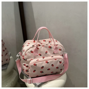 Close-up of pink corduroy fabric with red strawberry embroidery and adjustable strap
