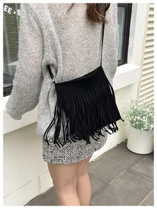 Detail shot of long black fringe tassels and matte texture on trendy crossbody bag