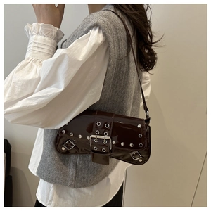 Detail view of dark brown patent leather underarm bag with silver rivets and metal buckle