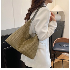 Detailed view of olive green woven leather hobo bag worn with a white blazer