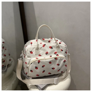 Detail of white corduroy tote bag with strawberry print and adjustable shoulder strap