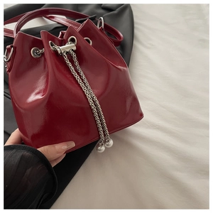 Detail of red patent leather bucket bag with silver chain drawstring and pearl charms