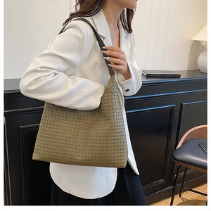 Detail of olive green woven Hobo tote bag with black strap on female model side view