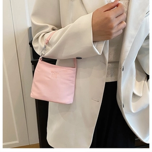 Detail of pink fabric handbag with Enjoy Life text held by model in white blazer