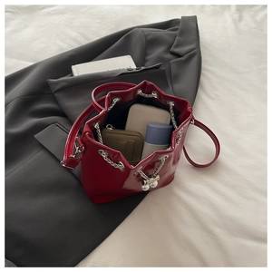 Internal view of red patent bucket bag with silver chain drawstring and pearl detail