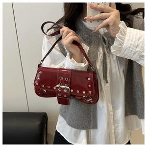 Close-up of deep red patent leather underarm bag with silver studs and metal buckle