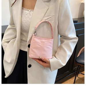 Detail of light pink mini handbag featuring enjoy embroidery and silver metal hardware