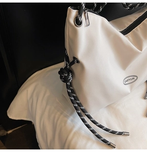 Dettaglio della borsa a tracolla bianca in nylon con cordino intrecciato e logo