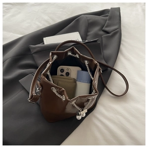 Detail of oil wax leather bucket bag with metal chain drawstring and pearl accents