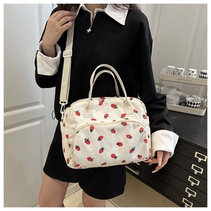 Detail of white corduroy tote with red strawberry print and adjustable shoulder strap