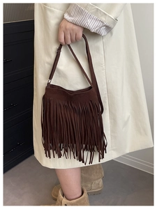 Detail view of deep brown suede shoulder bag with long fringe tassels and adjustable strap