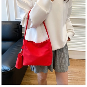 Detail of red nylon tote bag with matching detachable pouch shown on model in a living room