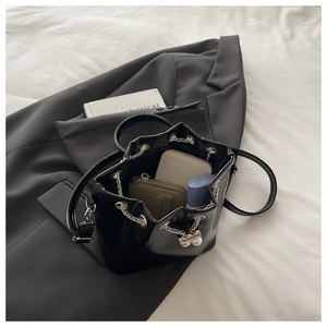 Detail of black glossy bucket bag interior showing spacious storage with pearl chain