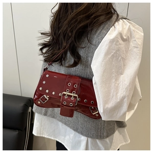 Detail of dark red patent leather shoulder bag with silver punk rivets and buckle