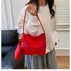Red nylon tote bag set with a matching small pouch worn by a model in a modern room