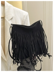 Detail shot of black fringe shoulder bag with long tassel texture on white blazer
