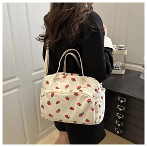 Detail of corduroy tote bag with strawberry print showing handles and shoulder strap