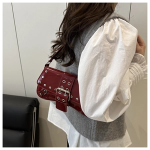 Detail of red patent leather shoulder bag with silver studs and large metal buckle