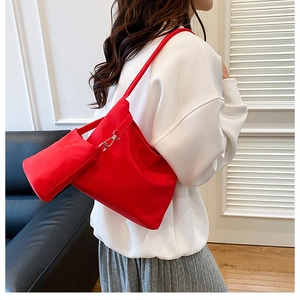 Detail showing the red nylon tote bag with a matching mini pouch clipped to the shoulder strap