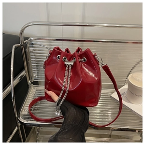 Dettaglio borsa a secchiello rossa lucida in pelle cerata con catena argento e coulisse