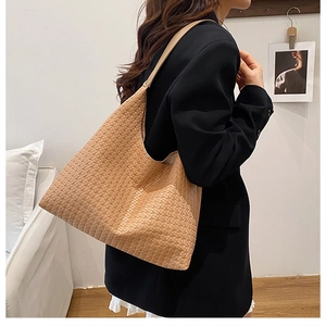 Detail view of a large woven tote bag in light brown showing the intricate texture