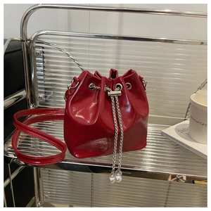 Detailed macro of red glossy patent leather bucket bag with silver chain and pearl accents