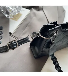 Detail of black crocodile pattern bag showing metal hook and adjustable leather strap