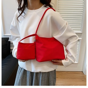 Detail of red nylon bucket bag with matching small zipper pouch worn with casual outfit