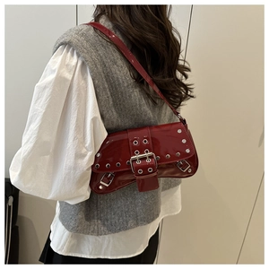 Close-up of red patent leather shoulder bag with metallic studs and buckle detail