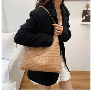 Detail of light brown woven tote bag hobo style showing texture and commuter style