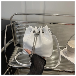 Dettaglio di borsa a secchiello bianca lucida con catena di perle e chiusura a coulisse