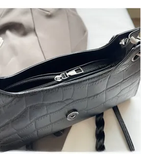 Detail of smooth metal zipper and magnetic closure on black crocodile pattern bag