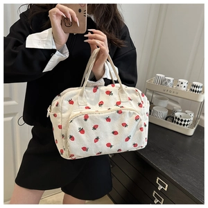 Detailed view of cream corduroy shoulder bag with red strawberry print on model