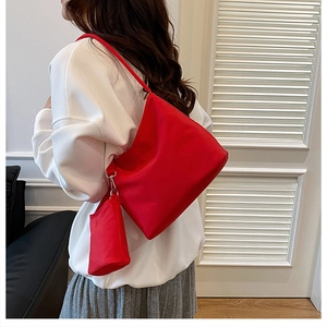 Detail of red nylon hobo bag and small detachable pouch worn by model in white sweater