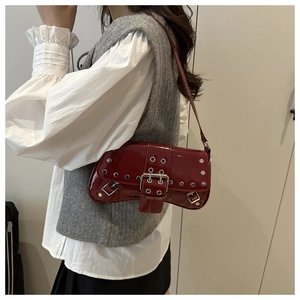 Detail of red patent leather shoulder bag with silver eyelets and metal buckle