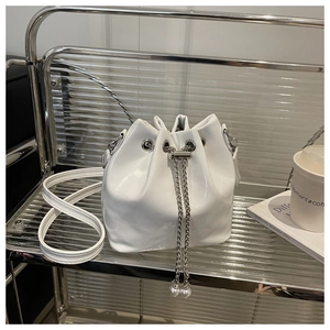 Detail of white glossy bucket bag with silver chain drawstring and pearl decoration