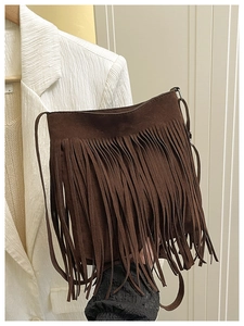 Detail of dark brown suede crossbody bag featuring dense bohemian style tassel fringe