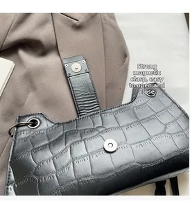 Detail of the strong magnetic buckle on a black crocodile pattern shoulder bag