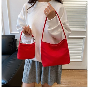 Detail of bright red nylon shoulder bag and matching mini pouch with silver hardware