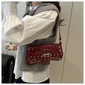 Detail view of burgundy punk shoulder bag featuring metallic studs and a large buckle strap