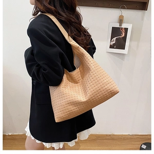 Detailed view of woven shoulder bag texture on model with a spacious tote design
